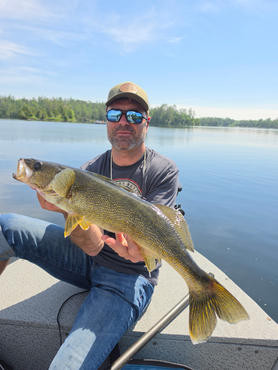 Guest holding a walleye on calm glass water
