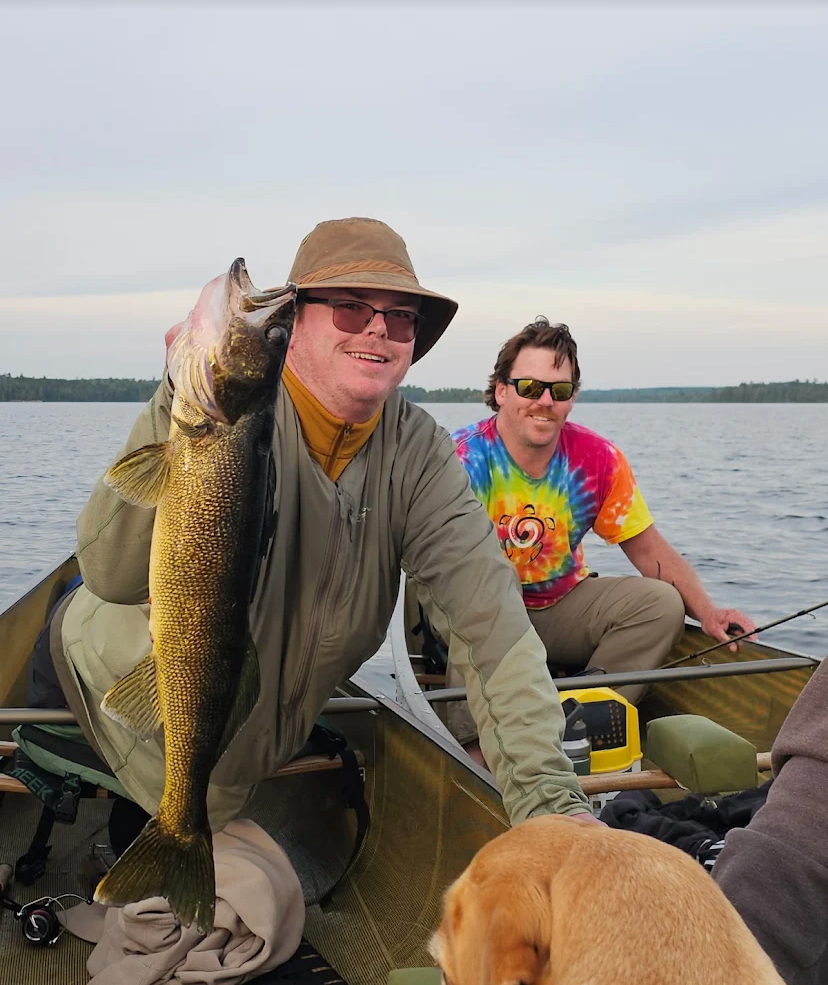 Guest holding a long golden walleye from a canoe on Bass Lake